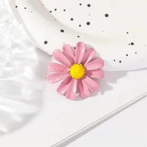 Close-up view of pink enamel daisy brooch showing exquisite yellow center details and smooth finish.