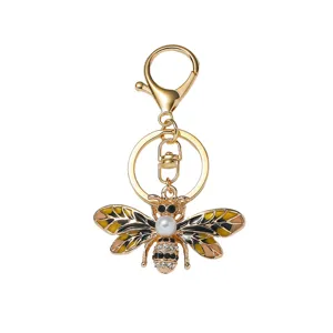 Detailed close-up of a gold-tone alloy bee keychain featuring enamel, pearl, and rhinestones.