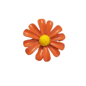 Detailed shot of a stylish minimalist enamel daisy brooch with vibrant orange petals and yellow.