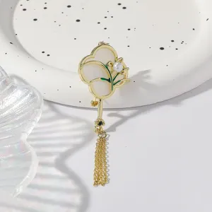 Exquisite Chinese style fan brooch detail, featuring pearl accent and delicate gold tassel.