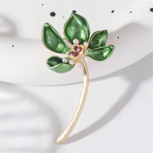 Elegant vintage lotus brooch with green enamel leaves, golden stem, and delicate pearl accents.