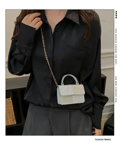 Detailed view of trendy color block mini handbag with metal chain strap worn by model.