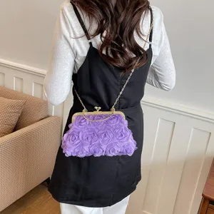 Dettaglio ravvicinato della borsa viola con fiori in tessuto e chiusura a scatto metallica.
