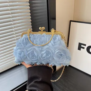 Dettaglio della borsa da sera blu con rose in rete, chiusura dorata e catena raffinata.