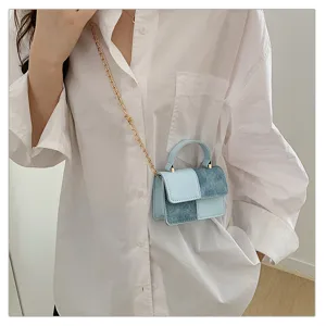 Detail shot of trendy patchwork handbag showcasing denim and leather texture with chain strap.