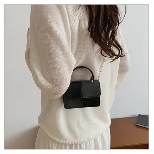 Detail shot of a chic color-block small square handbag with a chain strap and top handle.