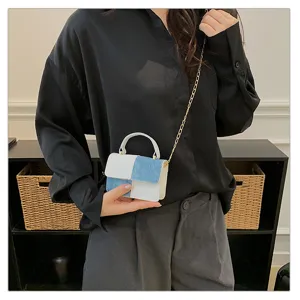 Detail shot of stylish color-blocked small square shoulder bag with metal chain strap.