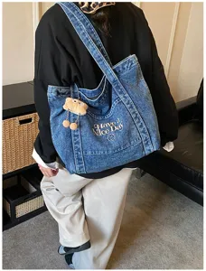 Denim shopper tas detail met borduurwerk letter ontwerp en ruime capaciteit voor dagelijks.
