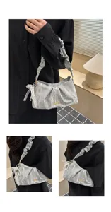 Detailed view of silver ruched shoulder bag with lace pearl charm and metallic logo accent.