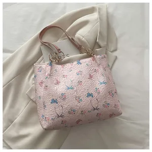 Rosa strukturierte Tasche Detail zeigt filigranen SchmetterlingsblumenDruck mit Schultergurt.