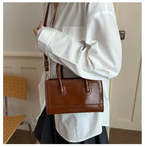 Close-up of a stylish brown leather small square crossbody bag detail, chic handbag design.