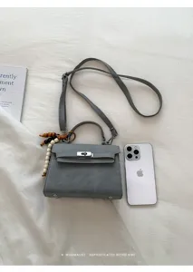 Detailed view of the stylish grey mini Kelly handbag with top handle and crossbody strap.