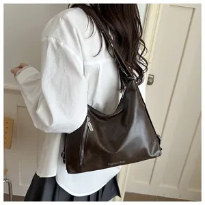 Vue détaillée du sac à épaule marron foncé tendance porté par le mannequin, grand format.