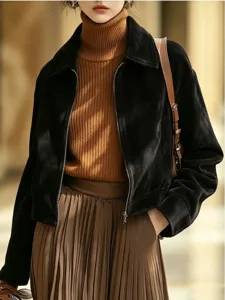Detail view of women black suede zip jacket with brown turtleneck sweater and pleated skirt.