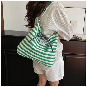 Green and white striped canvas shoulder bag for women, casual tote with bow drawstring closure.
