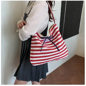 Detailed view of the red and white striped canvas shoulder bag with cute blue bow detail.