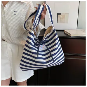 Details of the French style blue and white striped canvas shoulder bag with bow and strap.