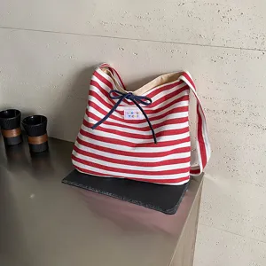 Red white striped canvas shoulder bag with black drawstring bow and letter label.