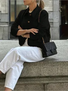 Detail shot of a vintage solid color suede blazer jacket paired with white pants outdoors.
