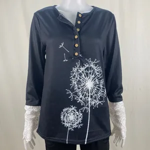Women's black long sleeve top detail featuring dandelion print, henley button neck, and lace cuffs.