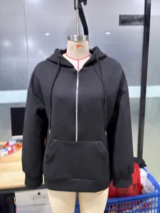 Dettaglio della felpa con cappuccio e zip nera testurizzata con motivo geometrico.