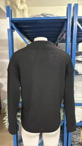 Detail shot of black ribbed knit sweater, featuring textured long sleeves for daily wear.