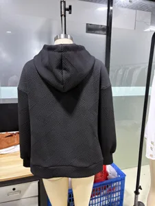 Vista dettagliata del retro della felpa nera con cappuccio e motivo geometrico, maniche lunghe.