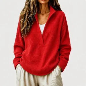 Close-up detail of the women's red waffle-knit sweater featuring a deep V-neck and long sleeves.