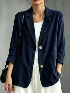 Dettaglio in primo piano della giacca blazer in corduroy blu scuro da donna con bottoni in legno.