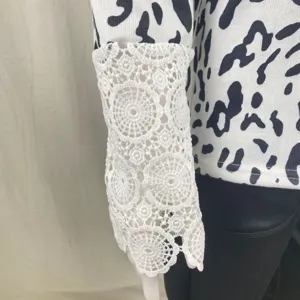 Detail shot of women's long sleeve top with white crochet lace cuff and black white print.