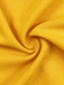 Golden yellow fabric texture detail shot, showcasing soft knitted surface and natural swirl drape.