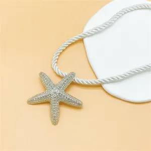 Close-up detail of the sparkling silver starfish pendant paired with a white twisted rope chain.