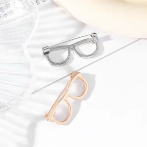 Detailed close-up shot of creative eyeglass frame brooches in gold and silver metal finishes.