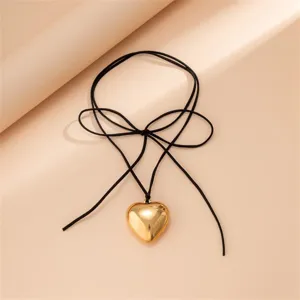 Collier pendentif cœur doré avec cordon en velours noir et nœud papillon élégant.