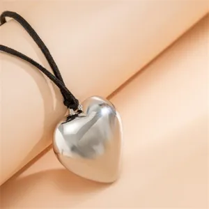 Gros plan d'un collier pendentif cœur argenté élégant avec un cordon en velours noir.