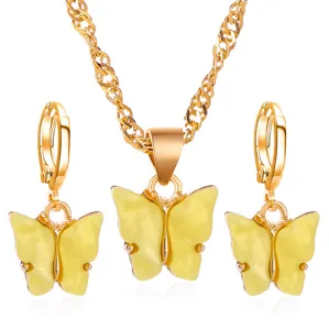 Detailweergave van gouden ketting en oorbellen set met gele acryl vlinder hangers eraan.