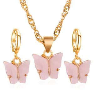Detailopname van de roze acryl vlinderhanger en de bijbehorende gouden ketting set.