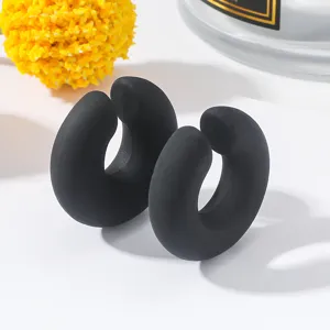 Orecchini a cerchio C spessi nero opaco in dettaglio, design geometrico minimalista.