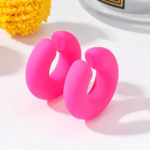 Primo piano dettagliato di orecchini a cerchio rosa vivo a forma di C con finitura opaca.