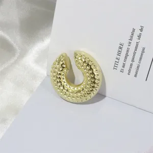 Goldfarbene strukturierte Ohrklemme Detailansicht, stilvoller Metall Ohrcuff Schmuck Design.