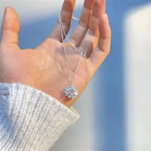 Detailed close-up view of the sparkling snowflake crystal pendant necklace on hand model.