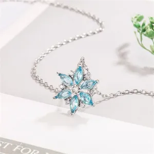 Detailed shot of a silver snowflake necklace with blue crystal gemstones, elegant winter jewelry.