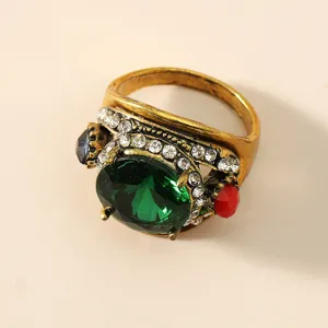 Anello vintage decorato con grande pietra verde, strass luminosi e dettagli unici.