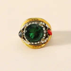 Primo piano dettagliato di un anello vintage esagerato con strass e una grande pietra verde.