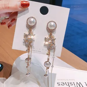 Detailed close-up of luxury rhinestone pearl snowflake long tassel earrings shining brightly.
