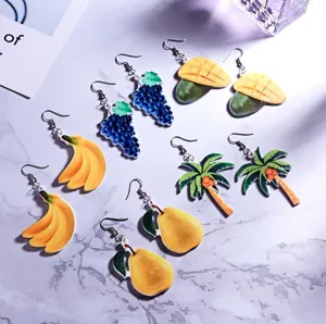 Detailopname van schattige acryl fruitoorringen met vrolijke banaan- en palmboomontwerpen.