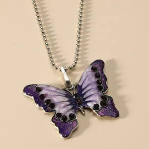 Gedetailleerde close-up van vintage paarse geëmailleerde vlinderhanger ketting met strass steentjes.