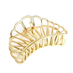 Detalle de pinza de pelo geométrica hueca de metal dorado, elegante diseño de concha.