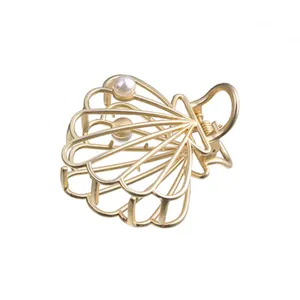 Pinza de pelo de concha de metal dorado calado con detalle de perla, diseño elegante.