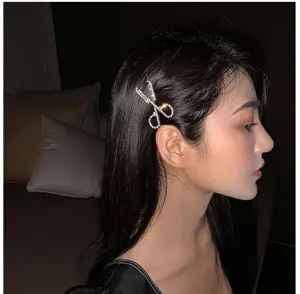 Detailaufnahme mit glitzernder Strass Schere Haarspange an dunklem Haar, stylisches Accessoire.